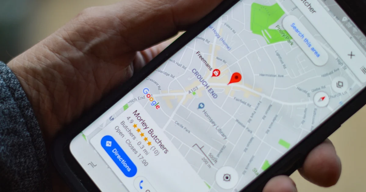 Mano sosteniendo un móvil con un mapa de navegación abierto en la calle