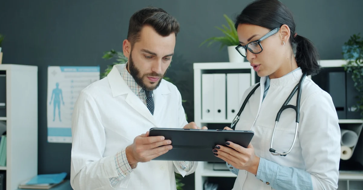 Dos profesionales sanitarios revisando datos en una tablet en la consulta