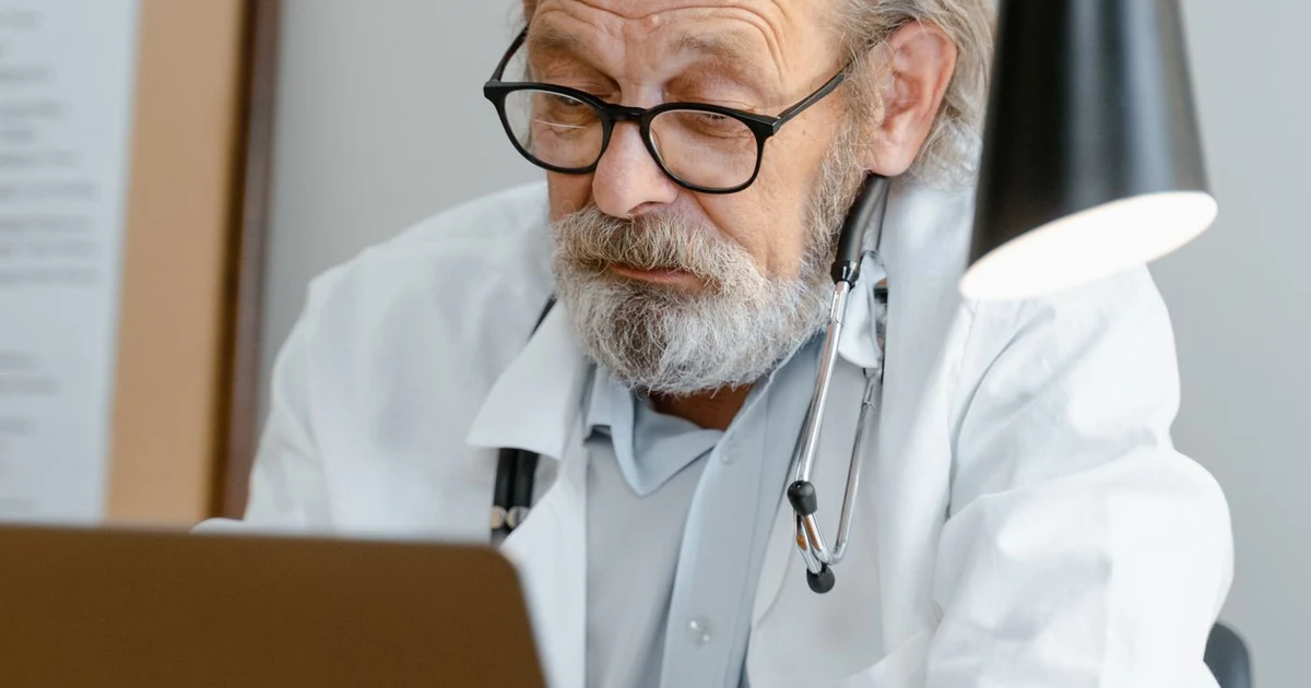 Profesional sanitario revisando presupuestos en un portátil en una consulta médica moderna